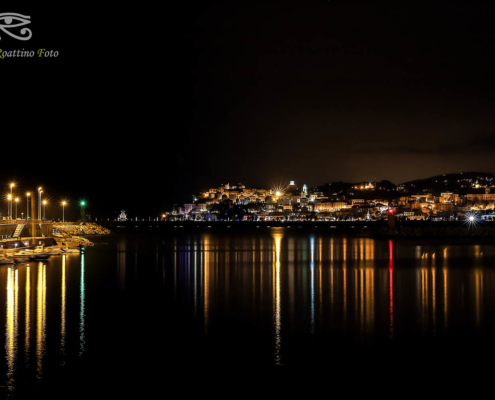 Imperia, l'ingresso del porto di Oneglia di notte con le luci che si riflettono sull'acqua